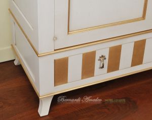 Classic wooden cabinet with white lacquered finish and hand-applied gold leaf
